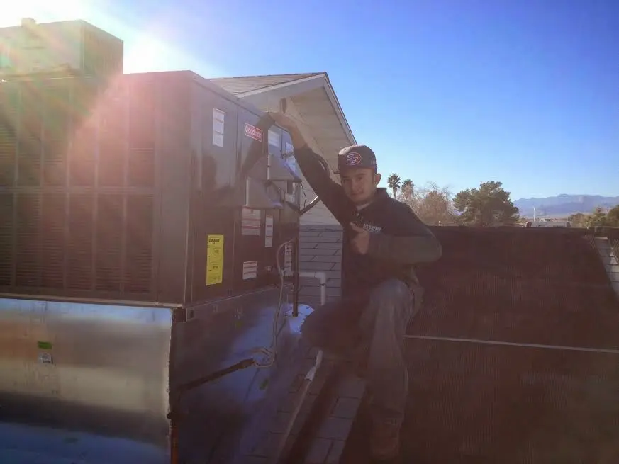 HVAC technician performing Air Duct Cleaning on a rooftop unit in Florissant